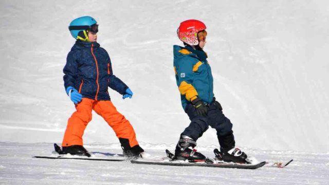 男の子二人がスノーボードで雪山を滑っている